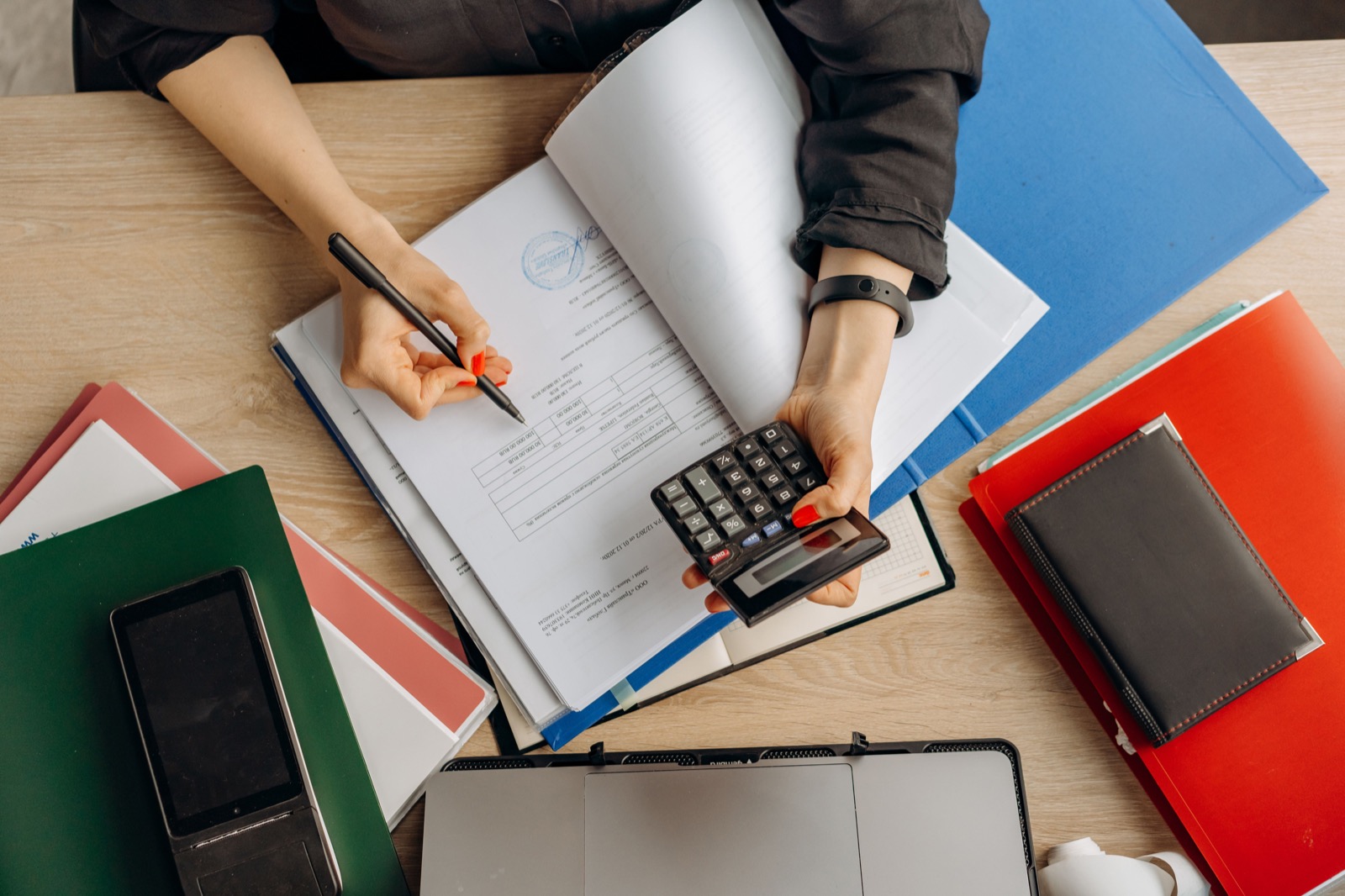 Profesional revisando documentación contable y realizando cálculos de control financiero